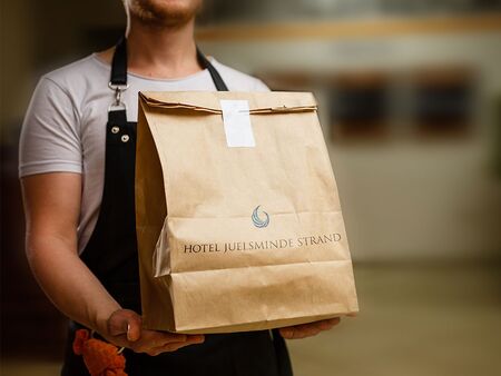 Чоловік із готелю Juelsminde Strand, який тримає сумку для їжі на винос