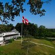 Hotel Juelsminde Strand mit Dannebrog im Fahnenmast und blauem Himmel