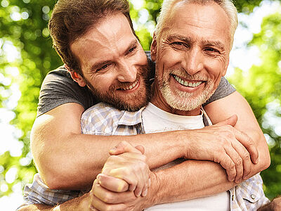 Adult man hugging his elderly father and smiling